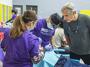 2 people working on a patient and 1 man observing