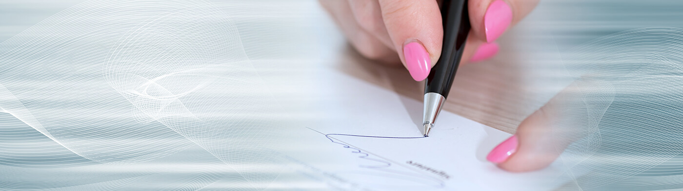 Close up of woman with pink fingernails signing a document