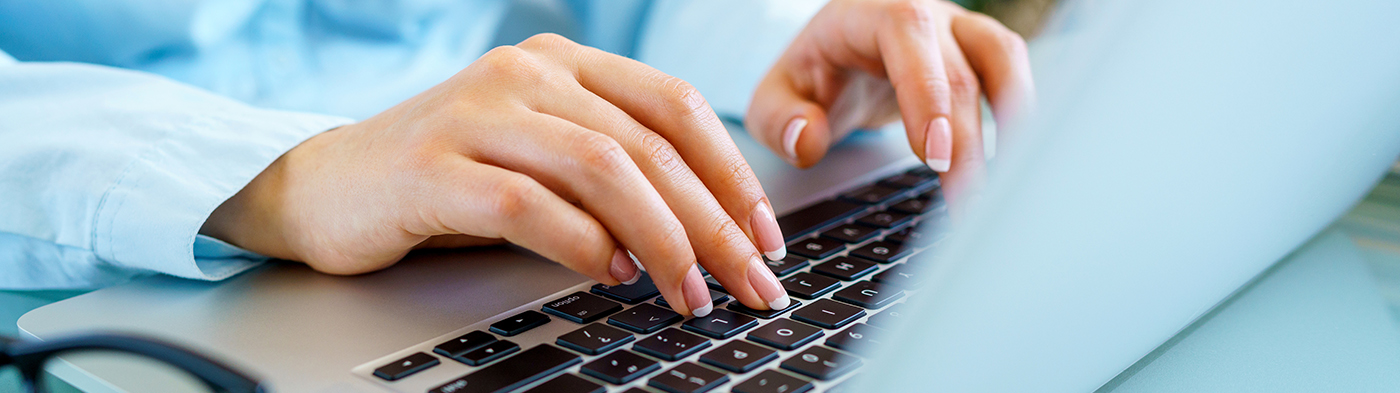 Close up view of woman's hands typing on laptop