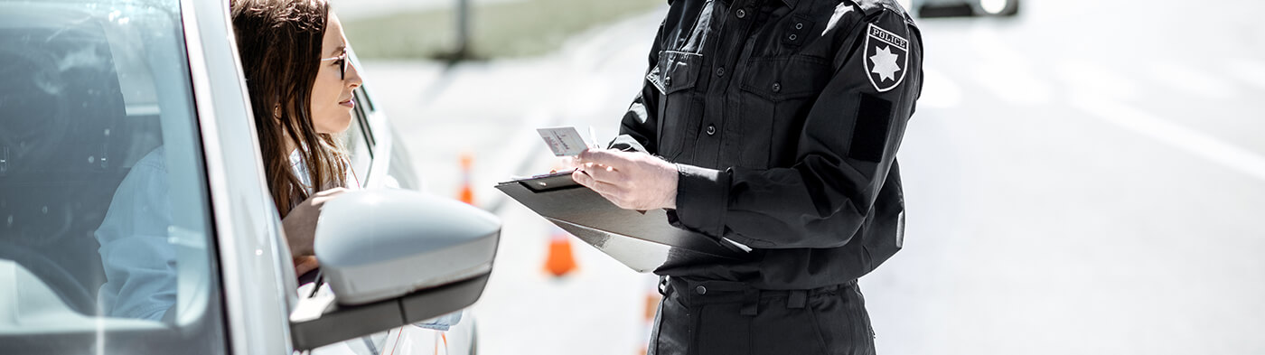 Woman leaning out car window speaking to police officer during traffic stop